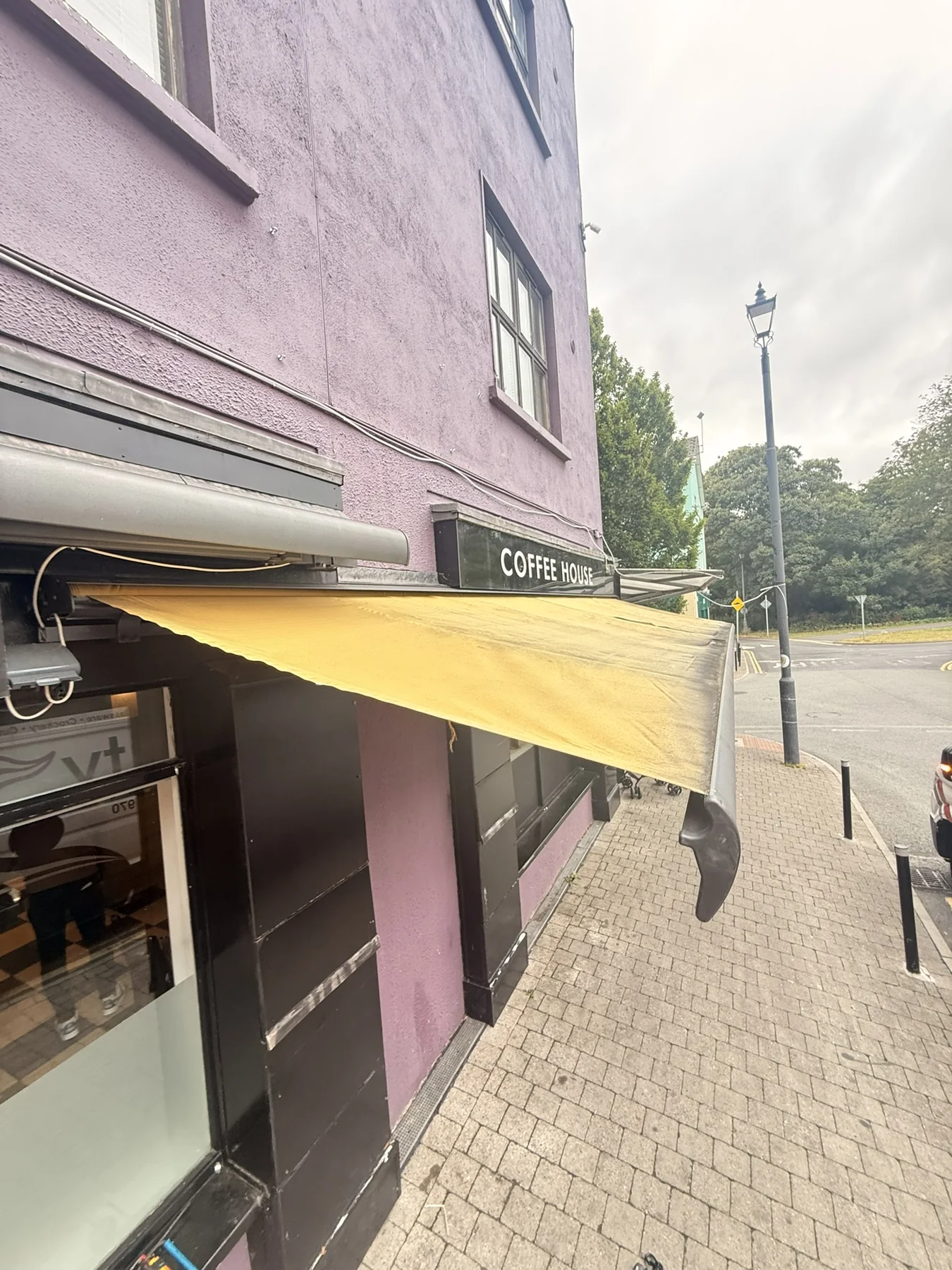 Faded commercial yellow awning on a coffee shop showing age and outdoor exposure