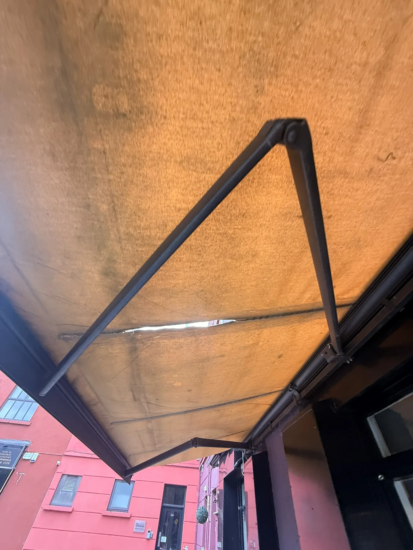 Commercial retractable awning with torn fabric before repair and re-covering