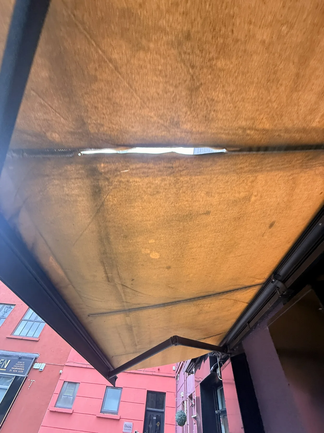 Close-up of torn commercial awning fabric and seam damage requiring assessment