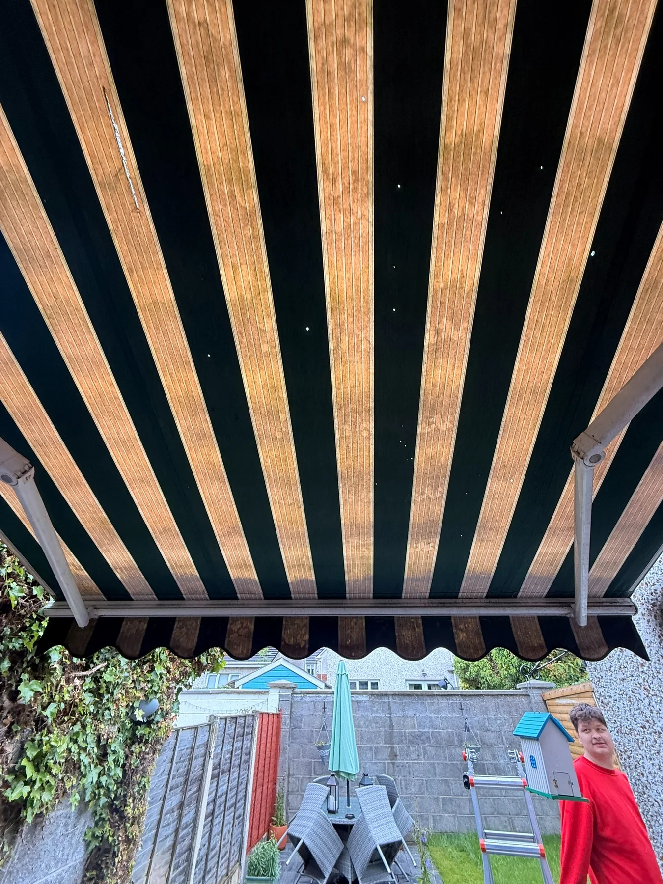 Weathered striped awning viewed from underneath showing fabric and arm condition