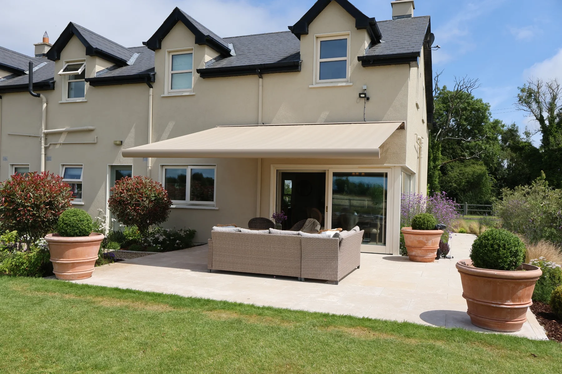 Full cassette awning shading a garden seating area beside a cream-coloured home