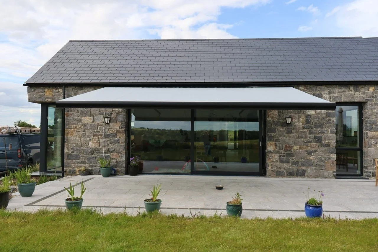 Large retractable awning installed above a patio beside a stone house in County Kildare