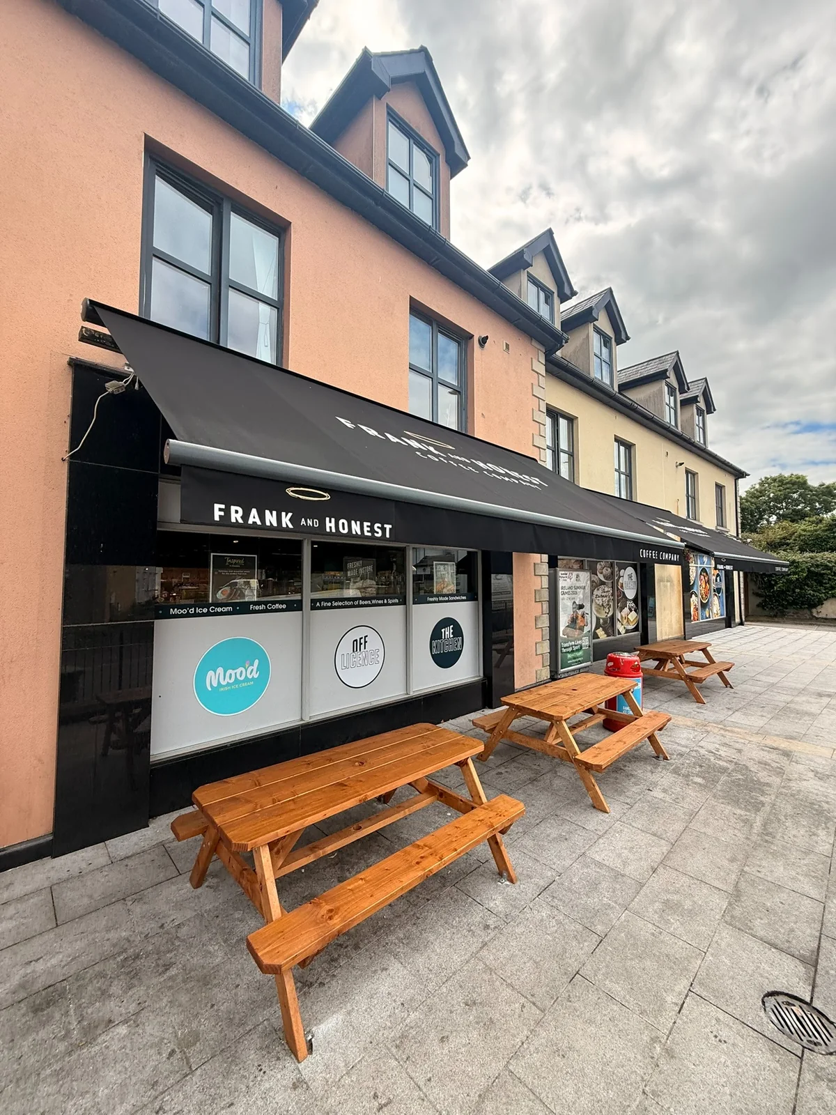 Black Frank and Honest commercial awning above outdoor picnic tables
