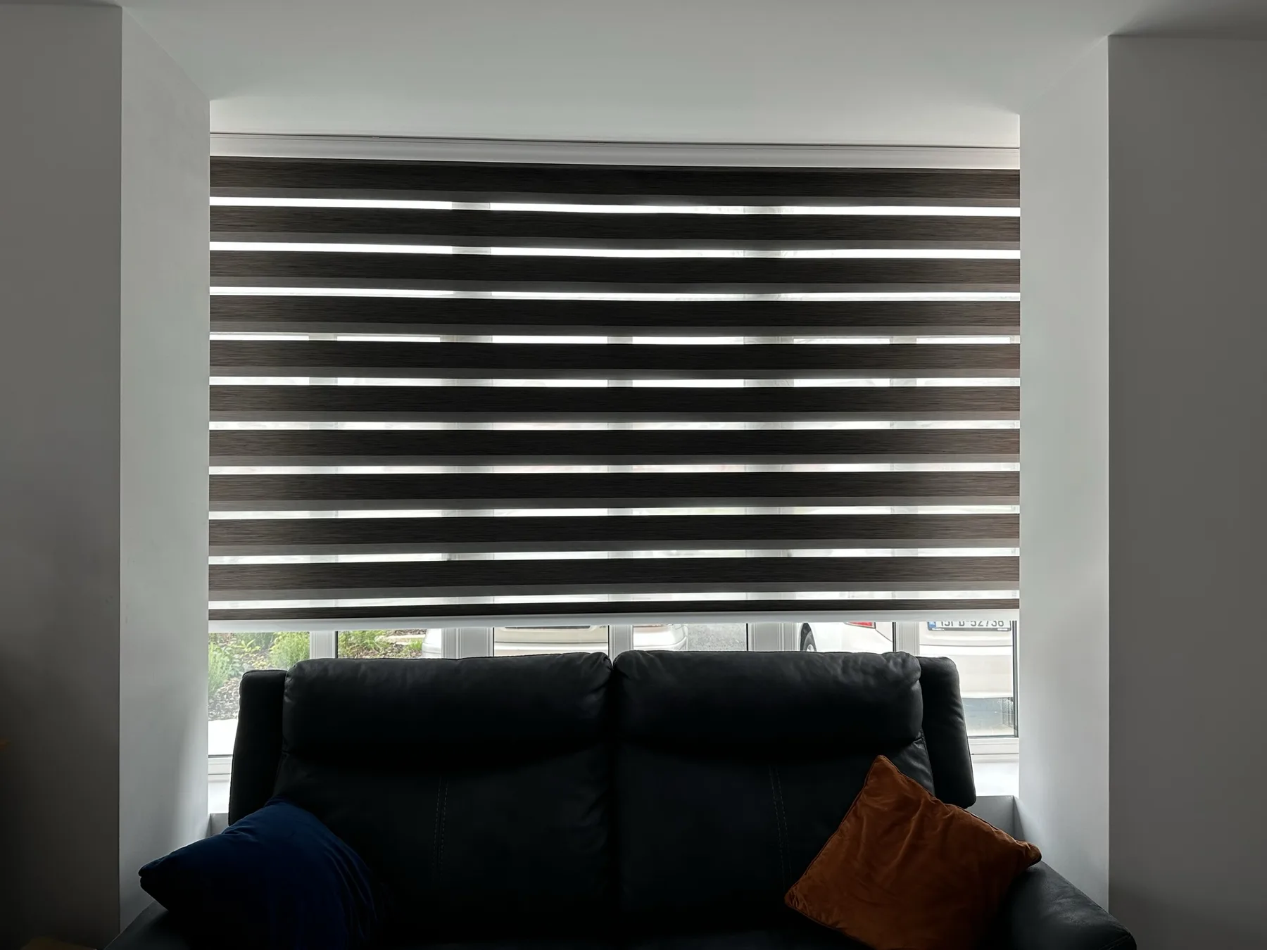 Dark day and night blind behind a living room sofa