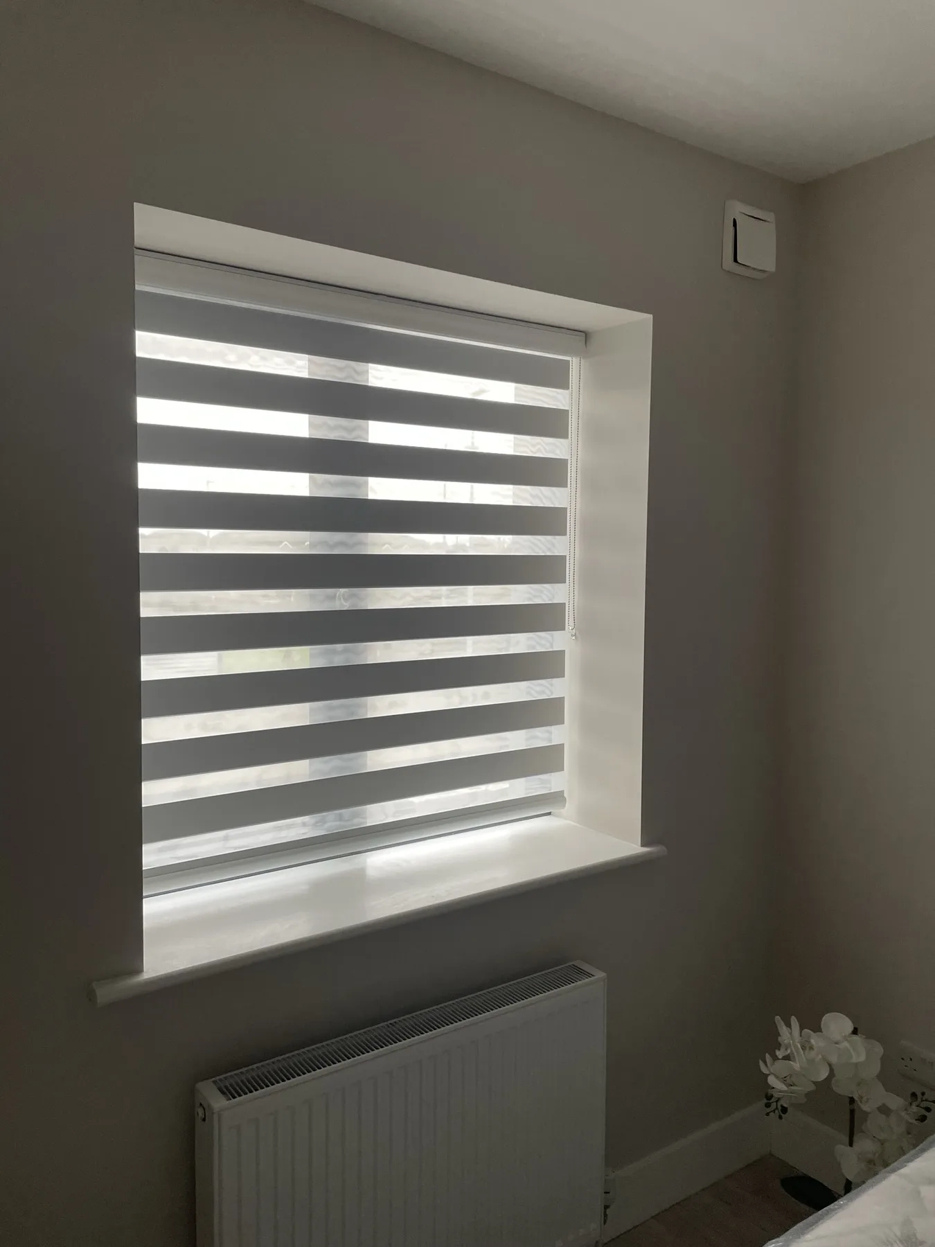 Grey day and night blind with sheer stripes aligned for filtered daylight