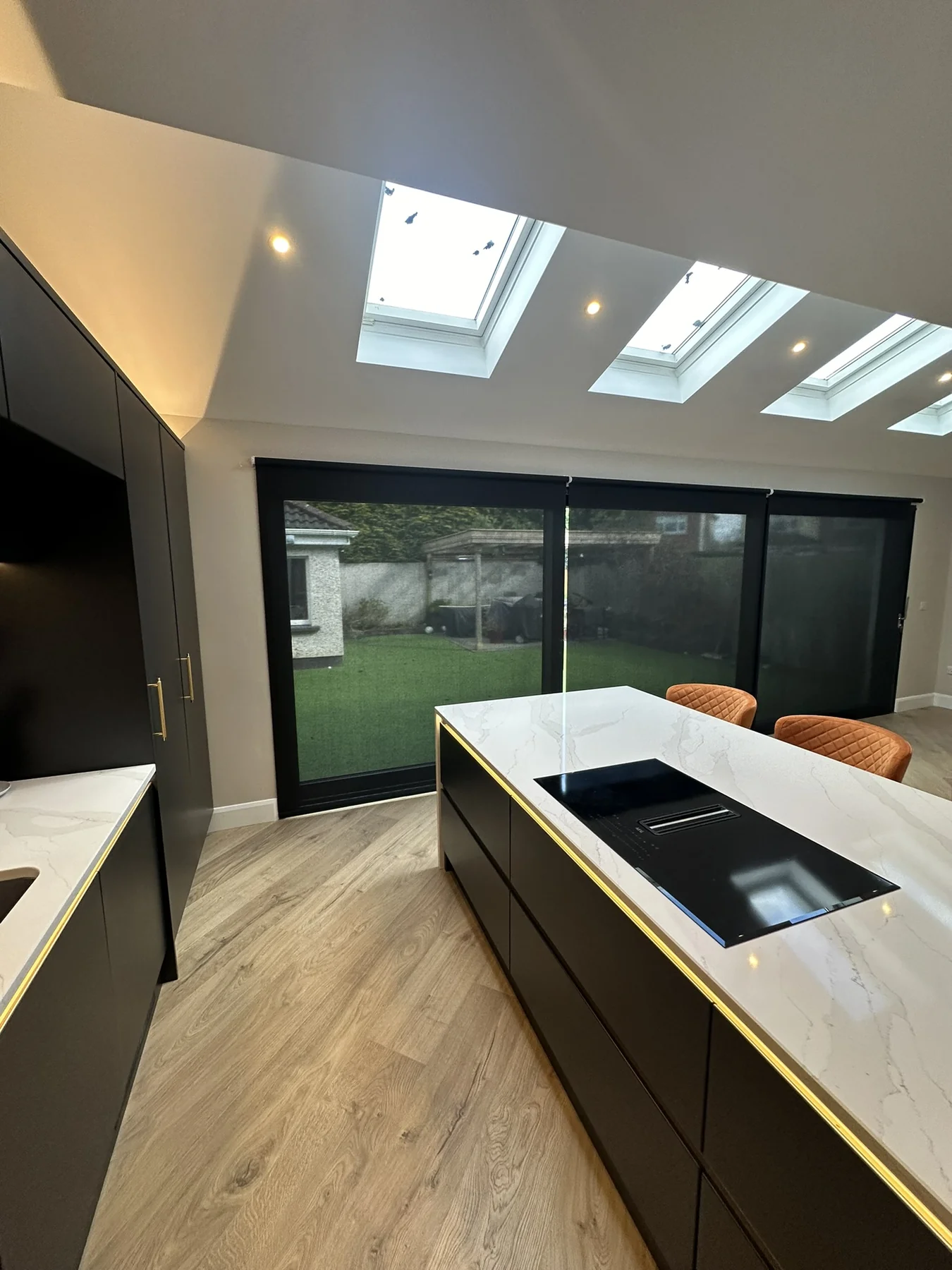 Dark motorised roller blinds across sliding doors in a modern kitchen extension