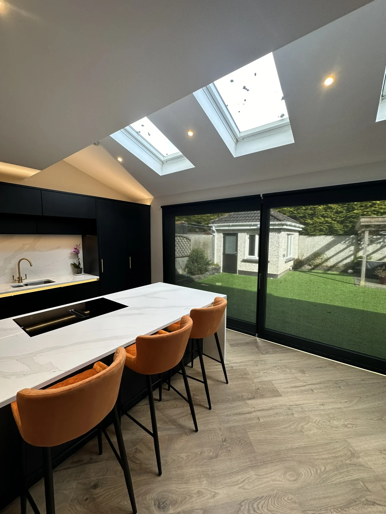 Dark roller blinds fitted across large sliding doors in a contemporary kitchen extension