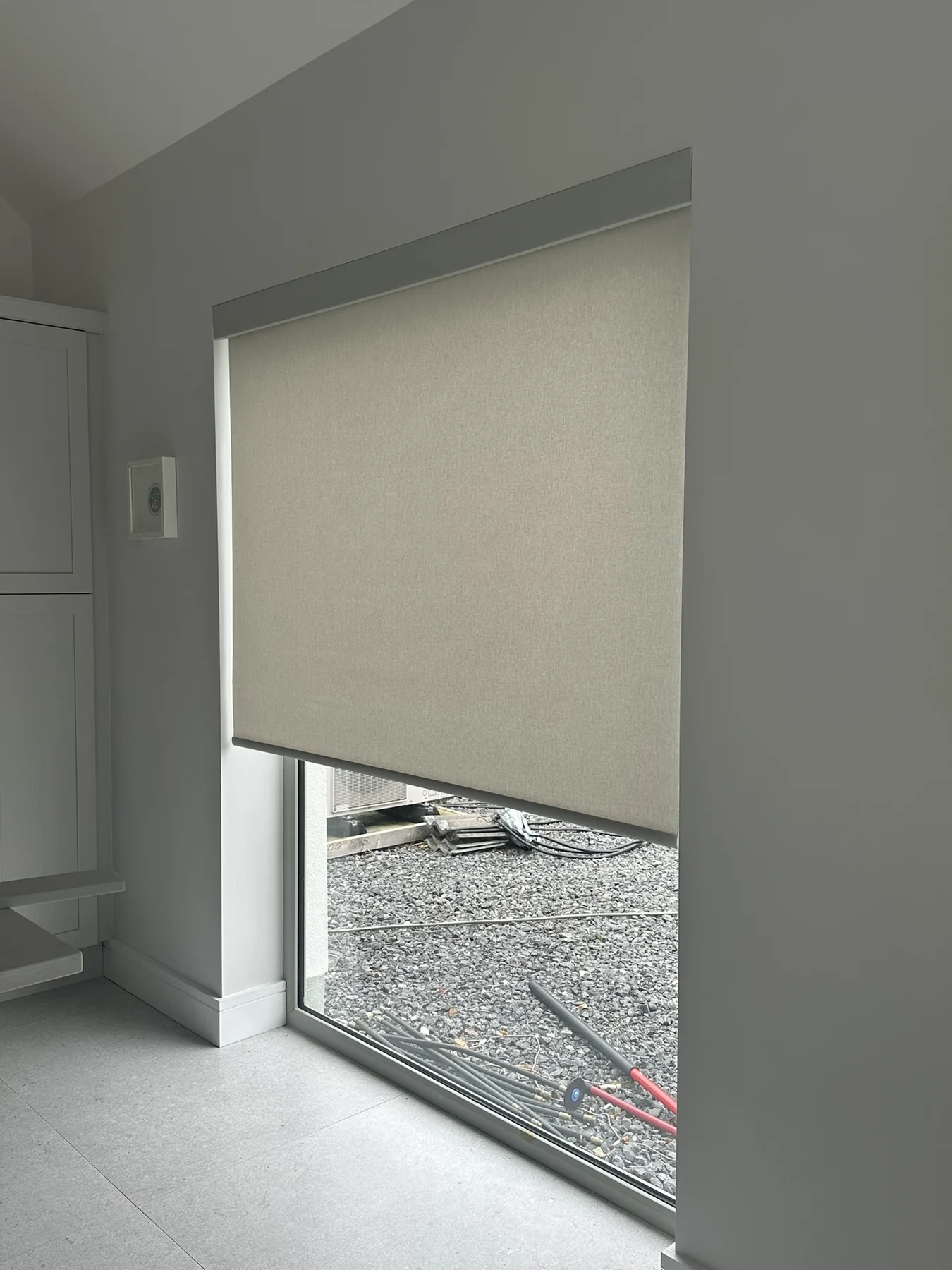 Light neutral roller blind fitted to a tall window in a bright modern interior