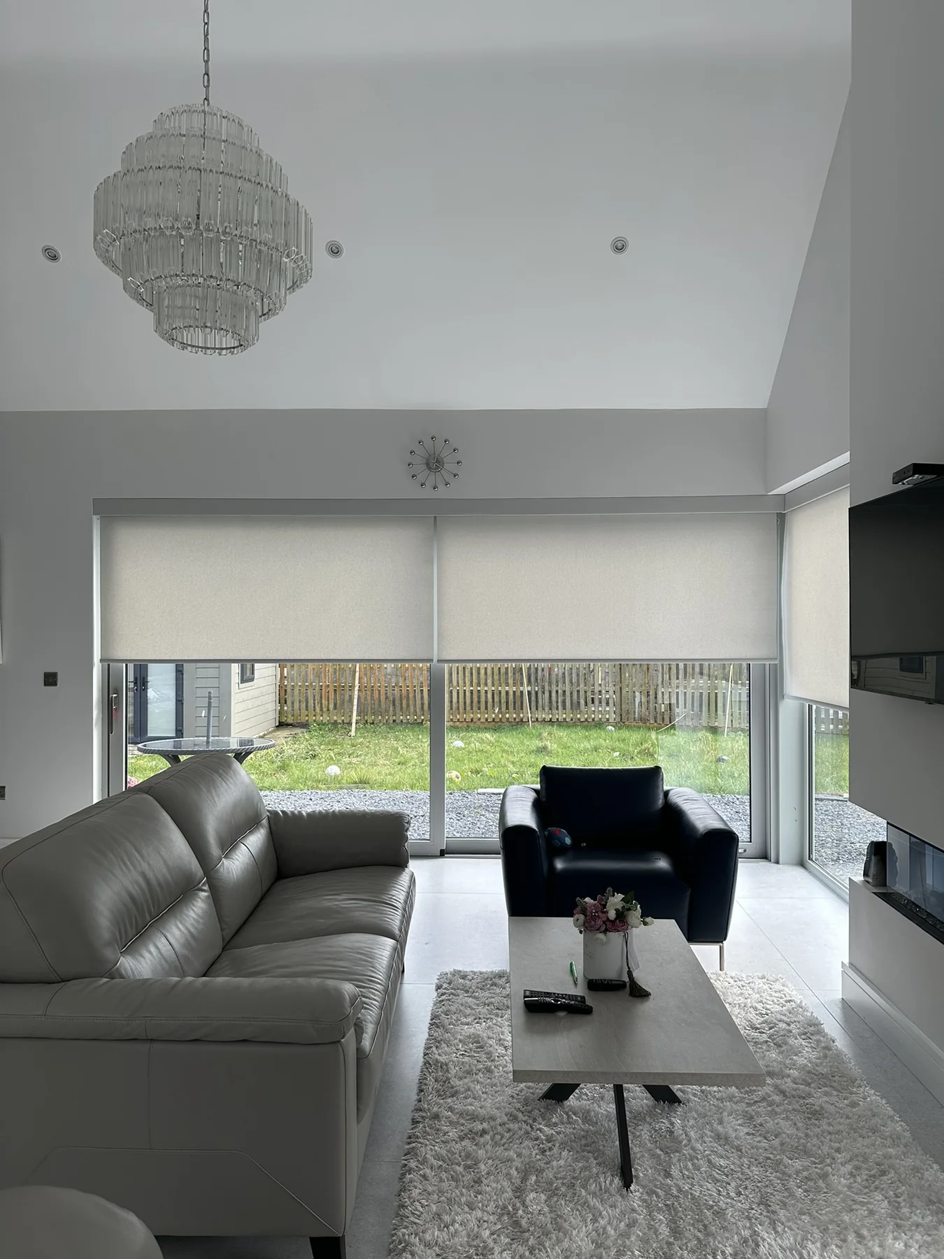 Neutral motorised roller blinds fitted across several windows in a bright open-plan room