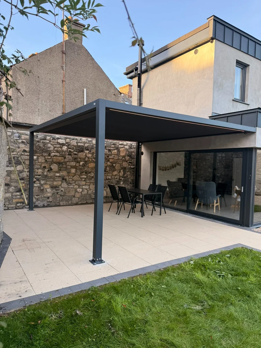 Pergola Square sheltering a dining table beside a garden
