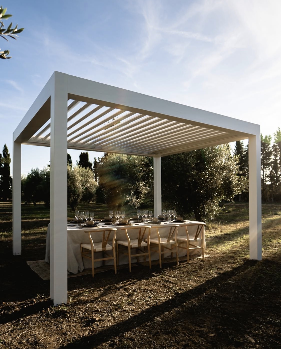 Self-supporting white bioclimatic pergola creating a premium outdoor dining setting