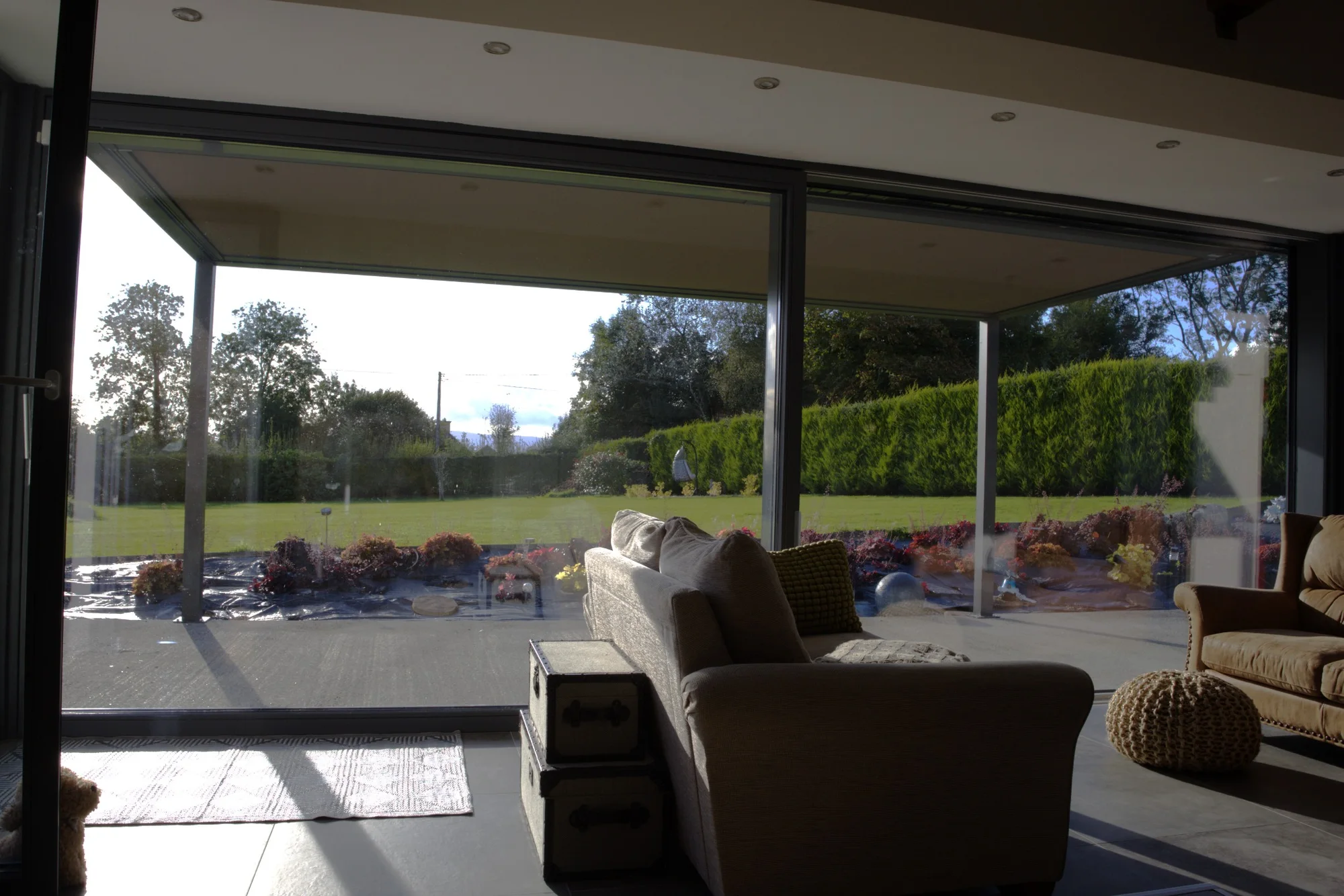 View from inside a home through wide glazing towards a Pergola Square covered terrace and garden