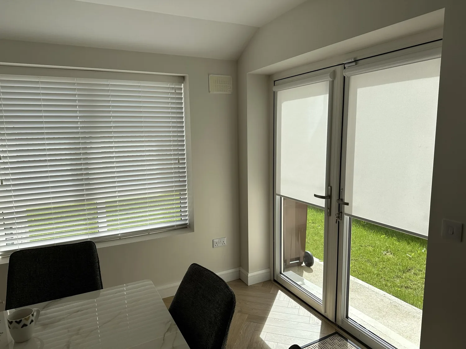 Roller blinds and Venetian blinds used together in a dining room