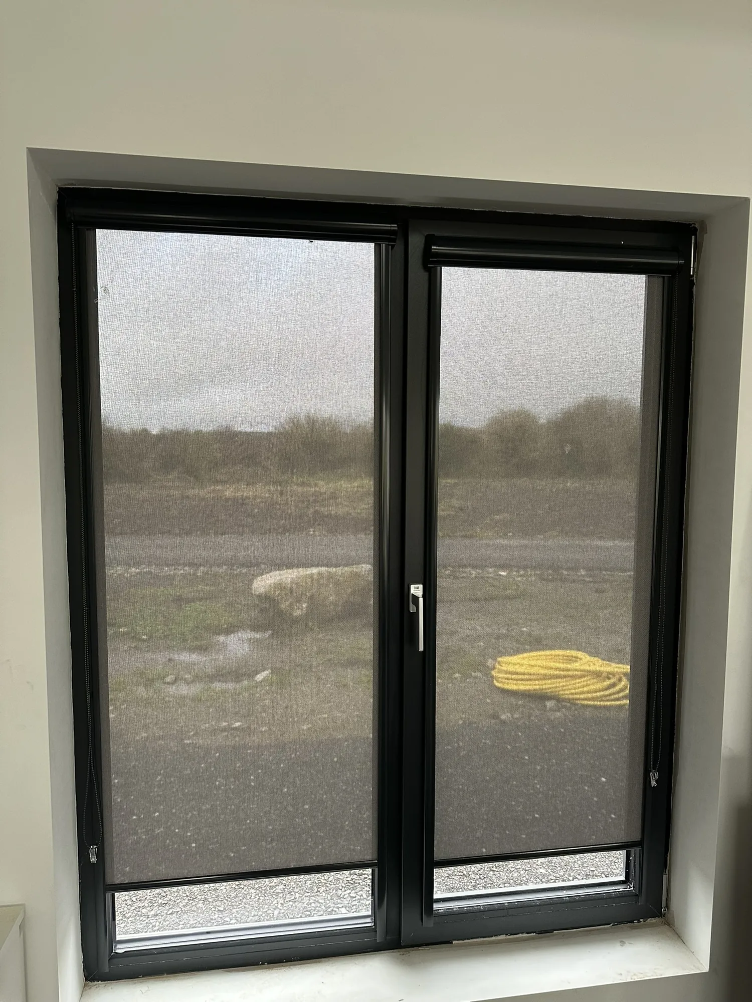 Screen roller blinds on black-framed windows filtering daylight