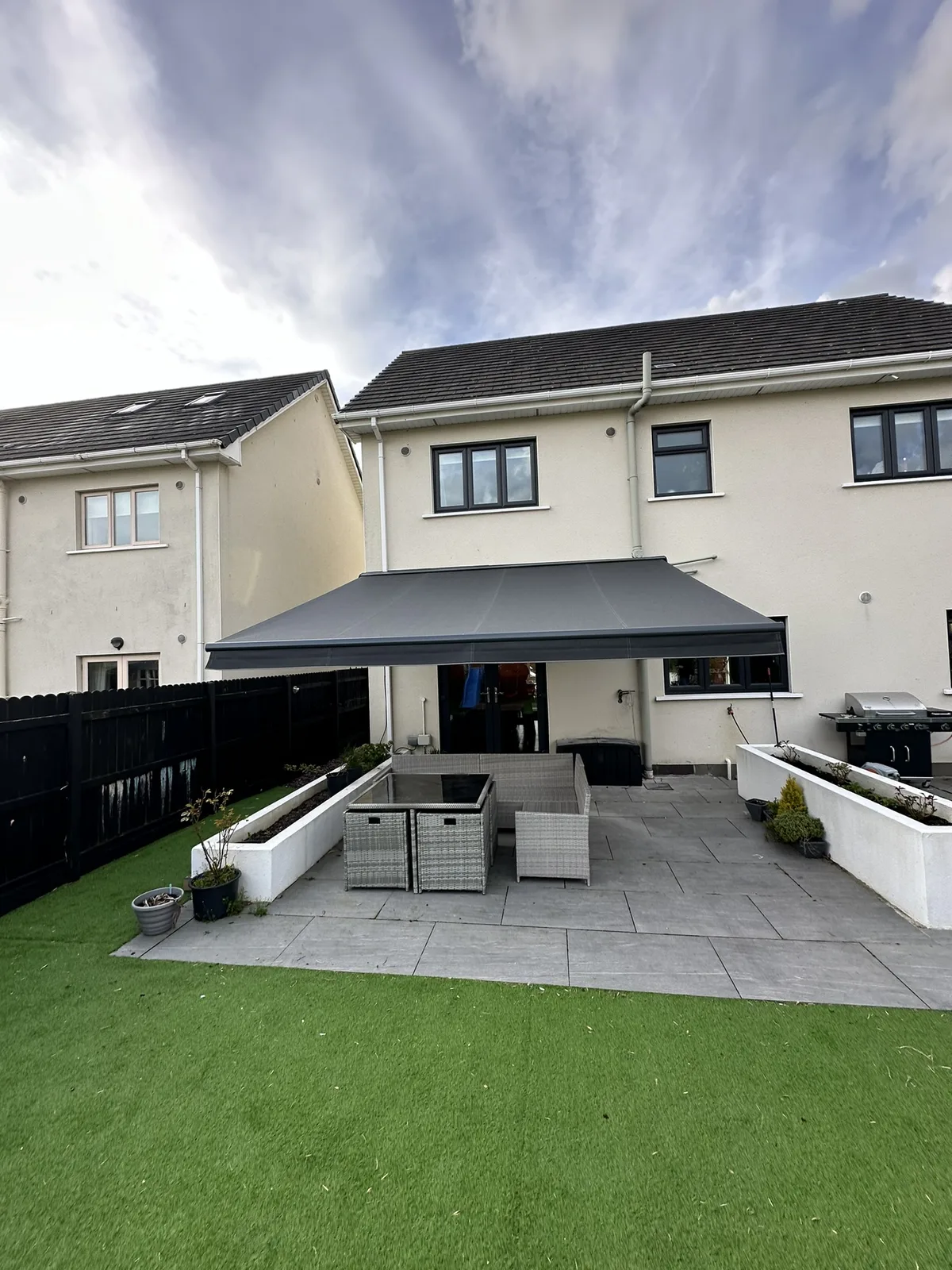 Dark grey semi cassette awning installed on extended brackets above a residential patio