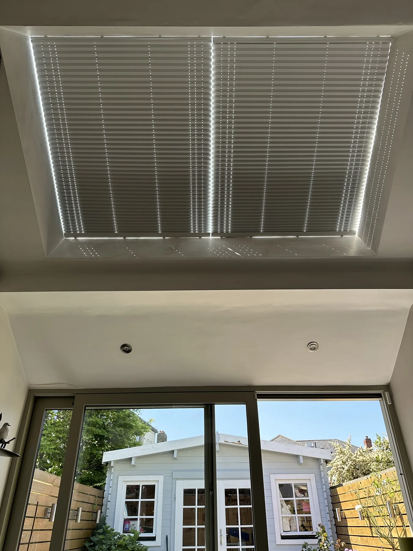 Pleated roof blinds filtering strong sunlight above patio doors