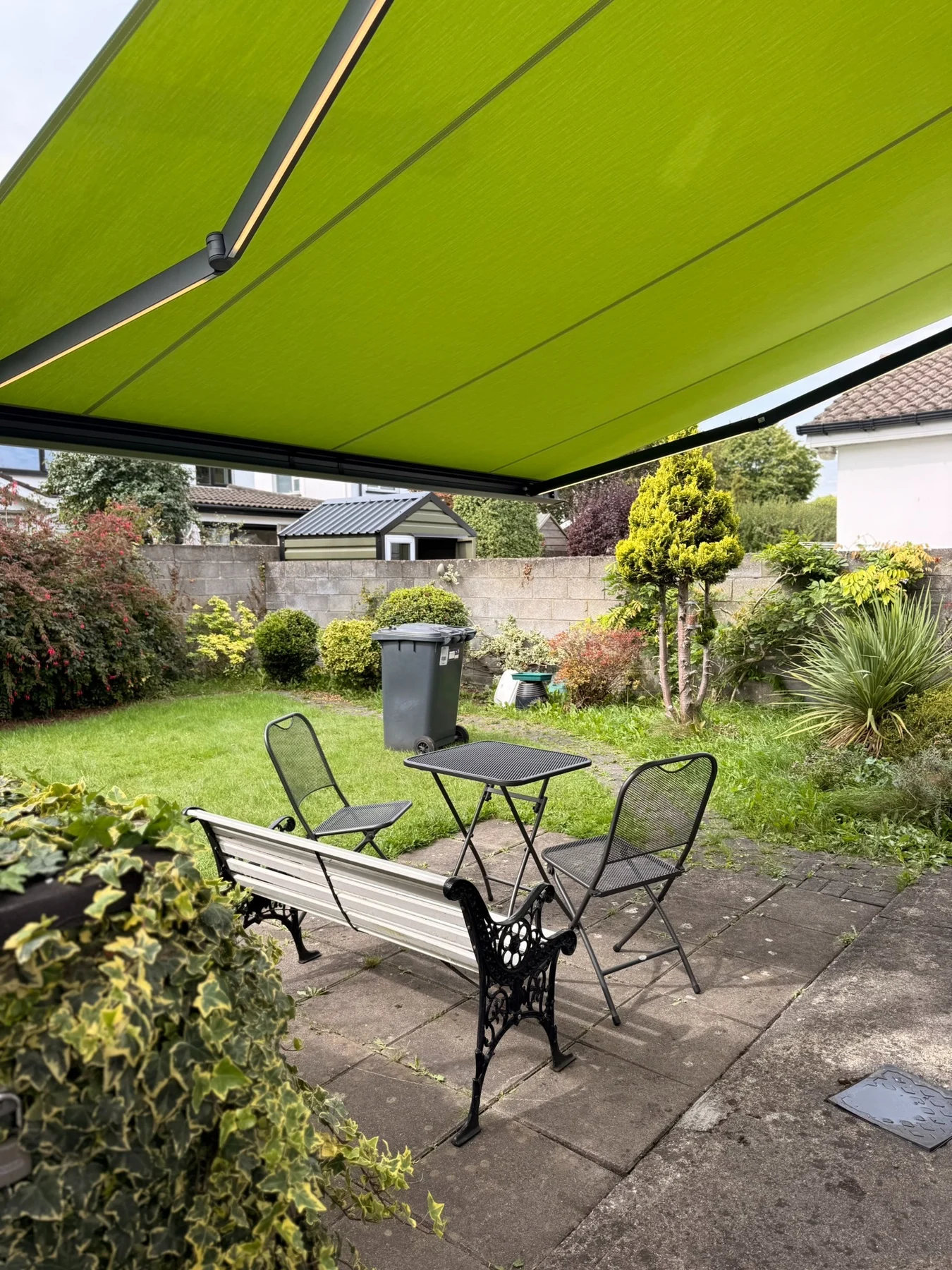 View from beneath a lime green SLIMLINE awning over a garden seating area in Kildare