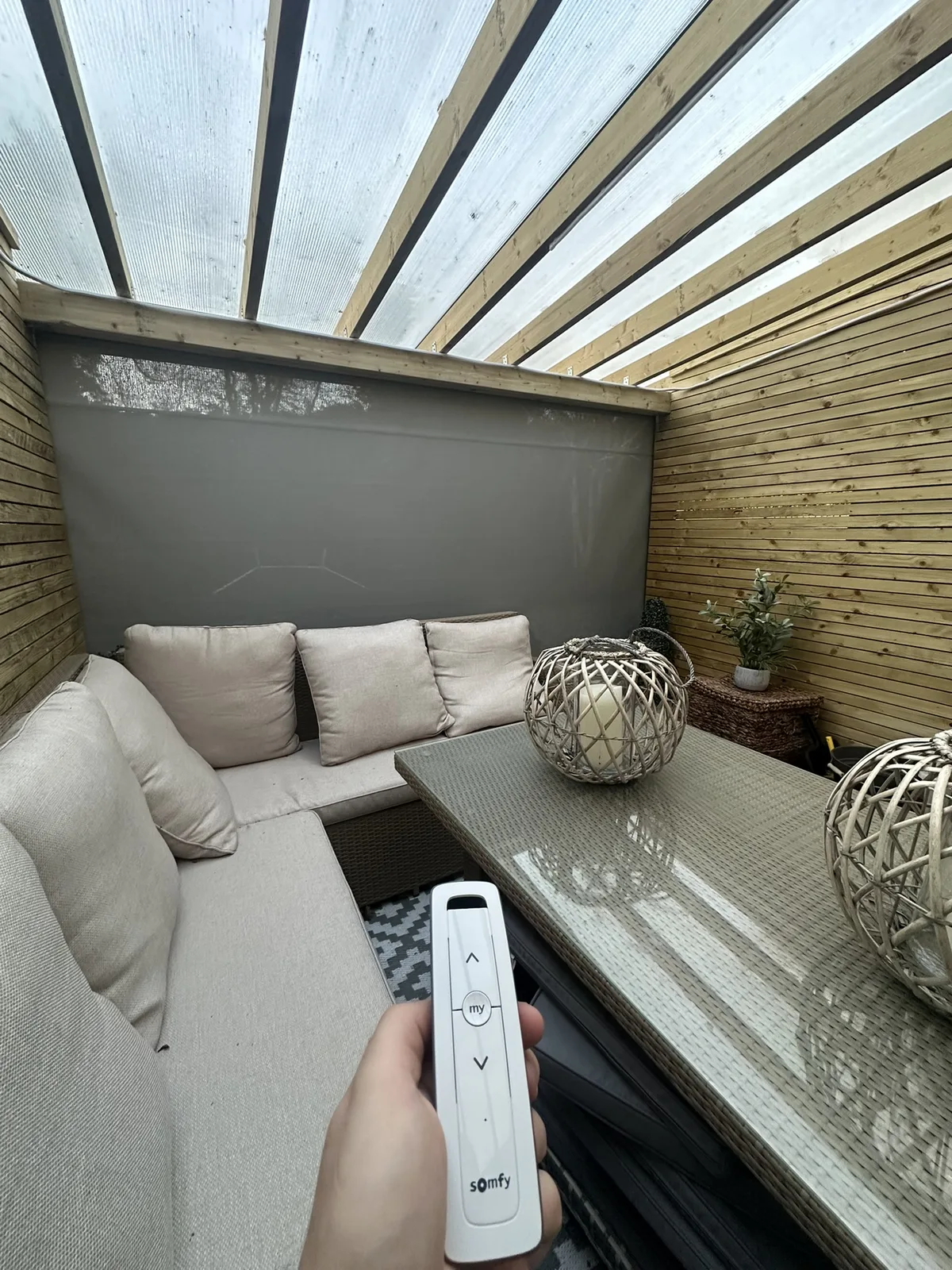 Somfy handheld remote controlling an exterior ZIP screen around a sheltered seating area