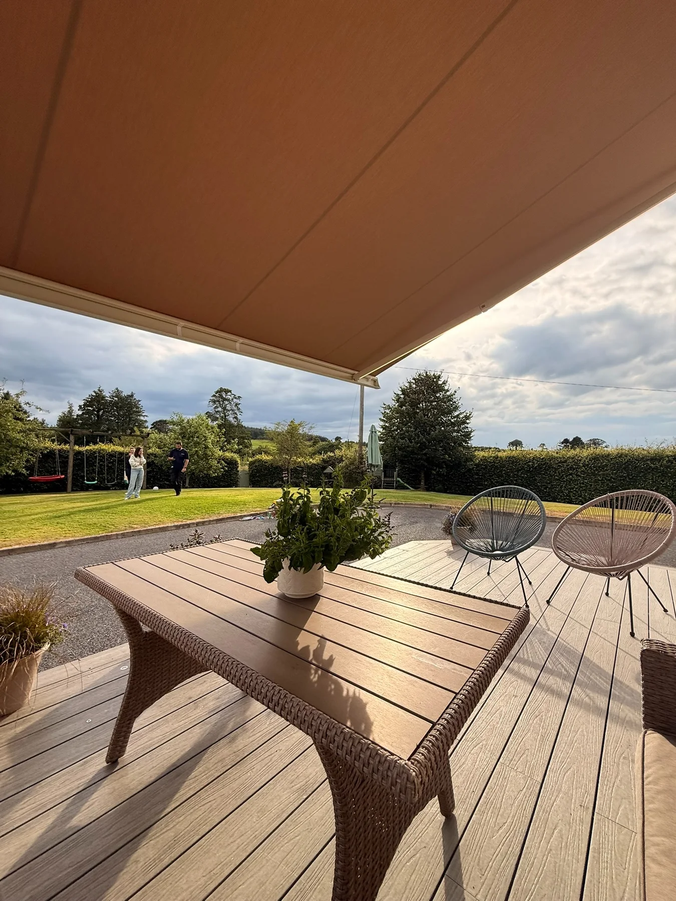 View from beneath a full cassette awning across a shaded residential patio