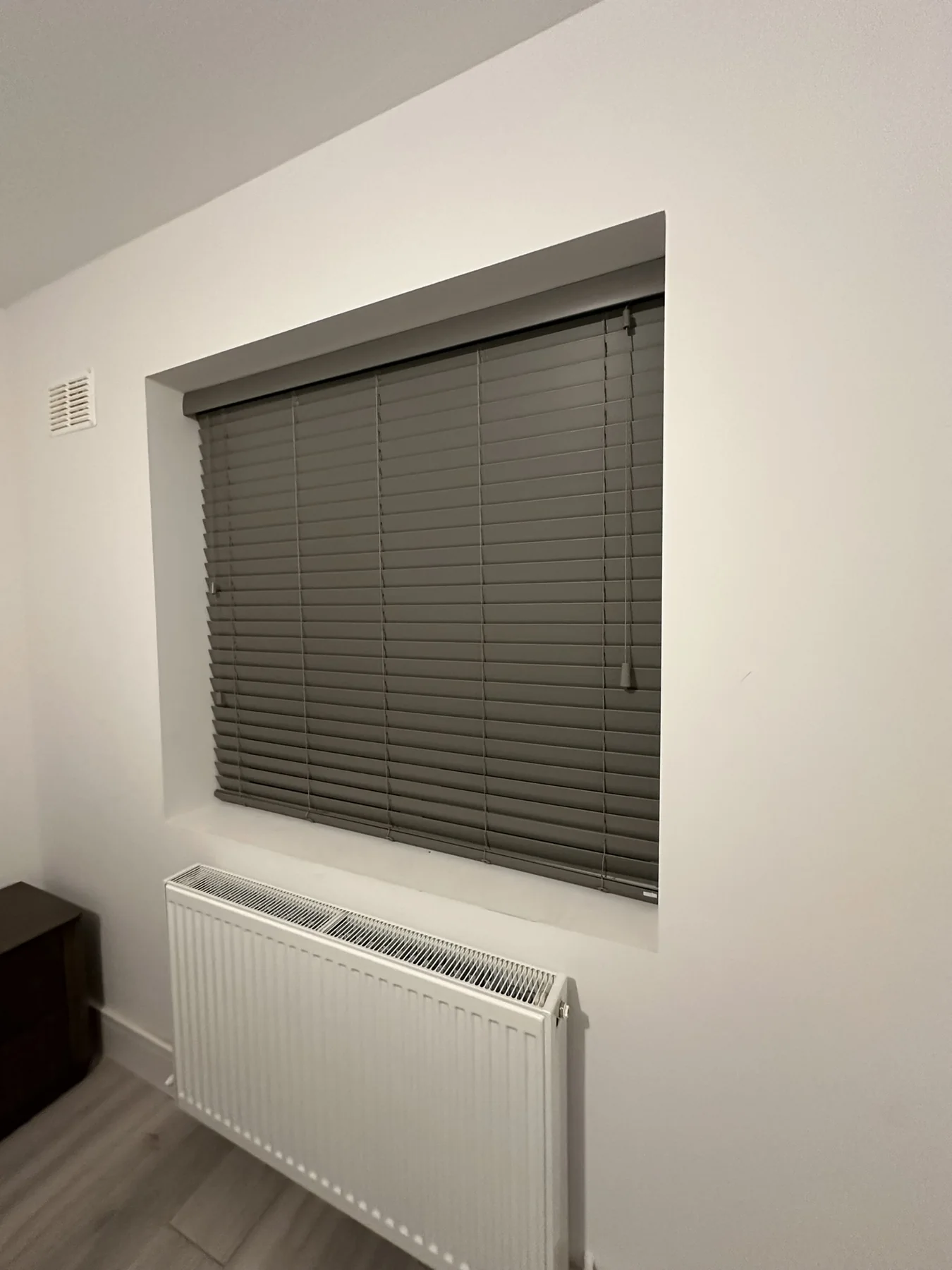 Dark grey Venetian blinds fitted in a white recessed window